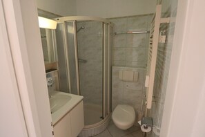 A small, enclosed bathroom with a shower, toilet, and sink. - Vonwyl (Davos)