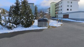 Zona residencial com chão coberto de neve, uma estrada e edifícios modernos.