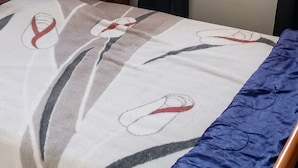A room with a bunk bed, a round window, and a bed with a patterned blanket.