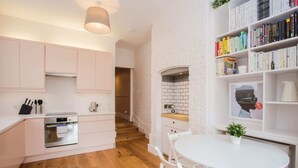 Una cocina moderna con armarios blancos, horno empotrado y comedor con mesa y sillas blancas.