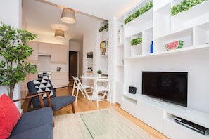 A modern living room with a flat-screen TV, a sofa, and a dining area with chairs and a table.