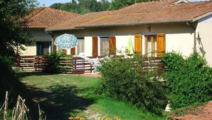 A two-story building with a tiled roof, a fenced courtyard, and a small garden area with yellow flowers. - Apartment with 3 bedrooms, 1 bathroom and garden with furniture and bbc (Toscana)