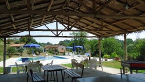 An outdoor covered area with a pool, lounge chairs, and a ping pong table. - Apartment with 3 bedrooms, 1 bathroom and garden with furniture and bbc (Toscana)