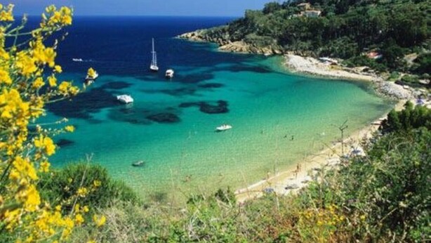 A coastal landscape with clear turquoise waters, boats, and a hilly backdrop. - Apartment with 3 bedrooms, 1 bathroom and garden with furniture and bbc (Toscana)