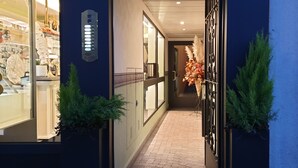 A corridor with a glass storefront on the left, a metal gate on the right, and a tiled floor. - Philips Apartment (Milan)
