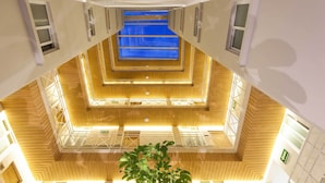 Ein mehrgeschossiges Atrium mit Holzvertäfelung und einem zentralen, blau beleuchteten Bereich.