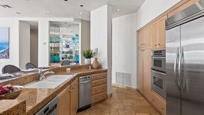 A modern kitchen with granite countertops, stainless steel appliances, and wooden cabinets. - LOWER LEVEL Pet Friendly Oceanfront Condo P921-0 (Oceanside)