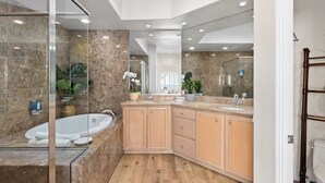 A modern bathroom with a freestanding bathtub, wooden vanity, and marble walls. - LOWER LEVEL Pet Friendly Oceanfront Condo P921-0 (Oceanside)