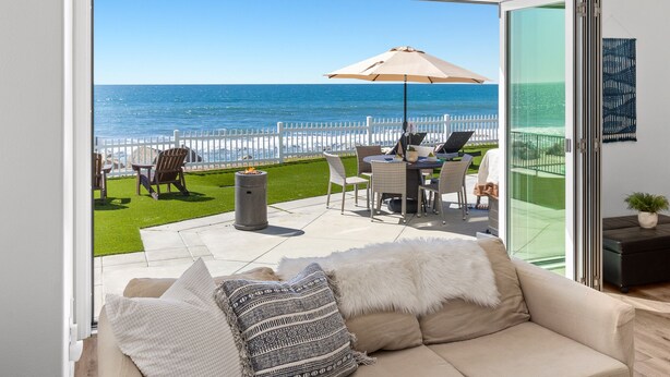 A balcony with a view of the ocean, a white fence, outdoor furniture, and a fire pit. - LOWER LEVEL Pet Friendly Oceanfront Condo P921-0 (Oceanside)