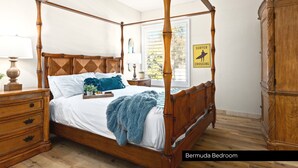 A Bermuda bedroom with a four-poster bed, wooden furniture, and a beach-themed sign. - LOWER LEVEL Pet Friendly Oceanfront Condo P921-0 (Oceanside)