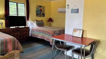 Habitación de motel con dos camas, un escritorio y sillas.