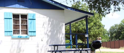 A house with a covered porch, a barbecue grill, and a picnic table.