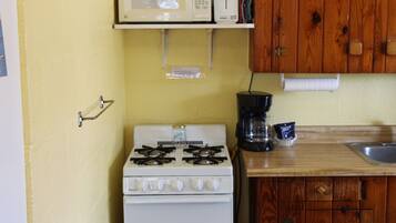 A compact kitchen with a white stove, a microwave, and a coffee maker on the counter.