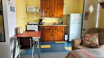 A compact kitchen with wooden cabinets, a stove, a microwave, and a refrigerator.