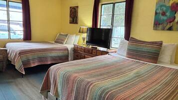 A room with two beds, a television, a dresser, and a painting on the wall.