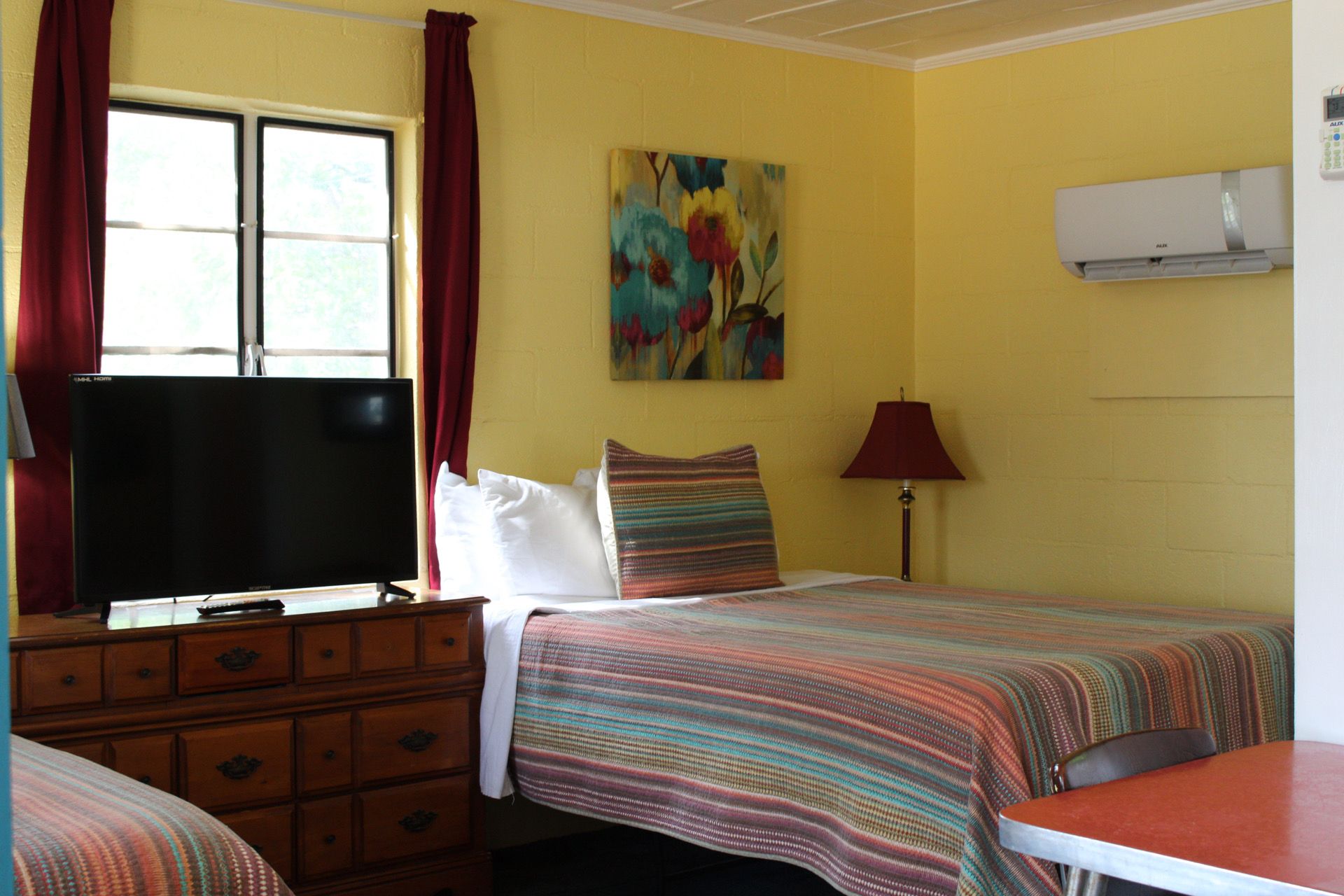 Una habitación con una cama, un tocador, un televisor y un cuadro en la pared.