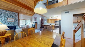 A spacious dining area with a wooden table and chairs, a stone wall, and a large pendant light.