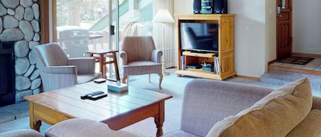 A living room with a stone wall, a fireplace, a television, and a sofa.