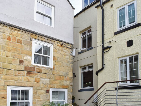 A corner of a building with stone and plaster facades, multiple windows, and a visible staircase. - 1 bedroom accommodation in Whitby (Whitby)