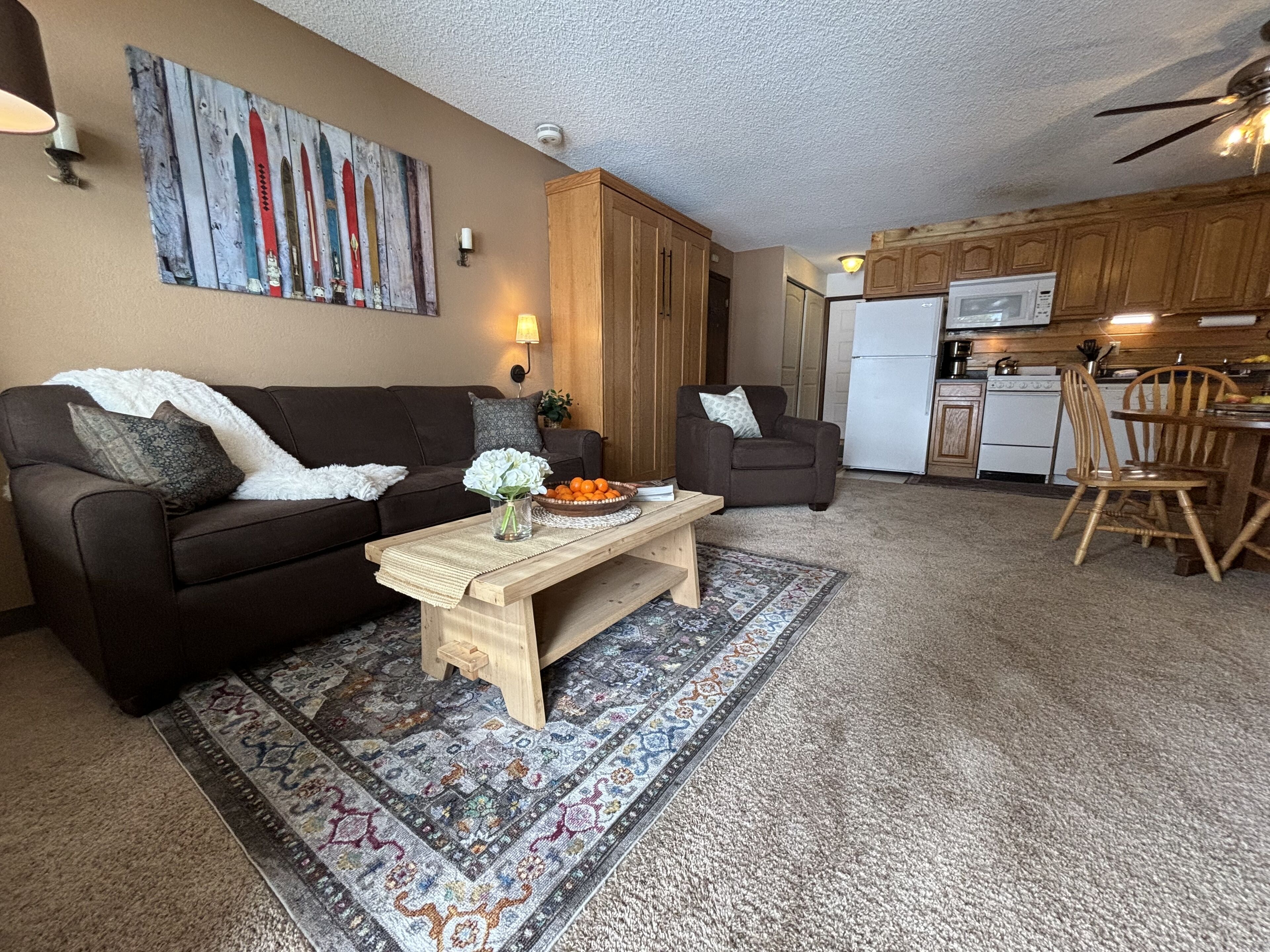 A cozy living room with a brown sofa, a wooden coffee table, and a patterned rug.