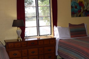A room with a bed, a dresser, a window with curtains, and a painting on the wall. - Sunfish Studio 6: Pool, Private Dock, Firepit! (Kingsland)