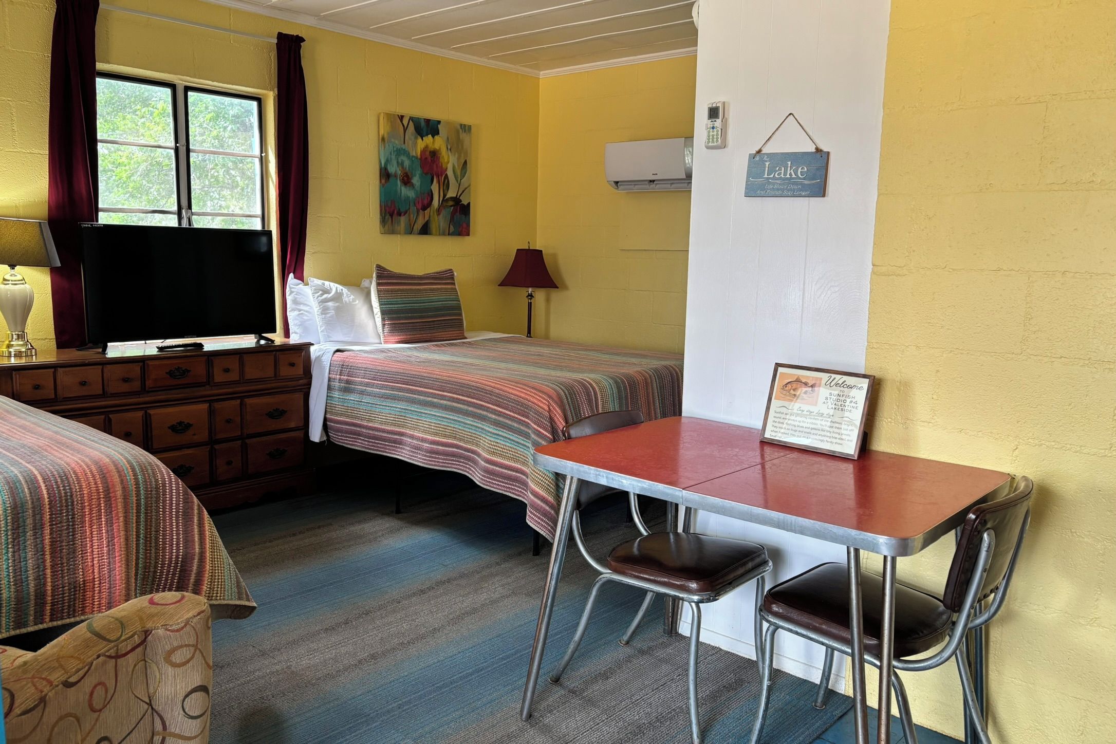Habitación de motel con dos camas, un escritorio y sillas.