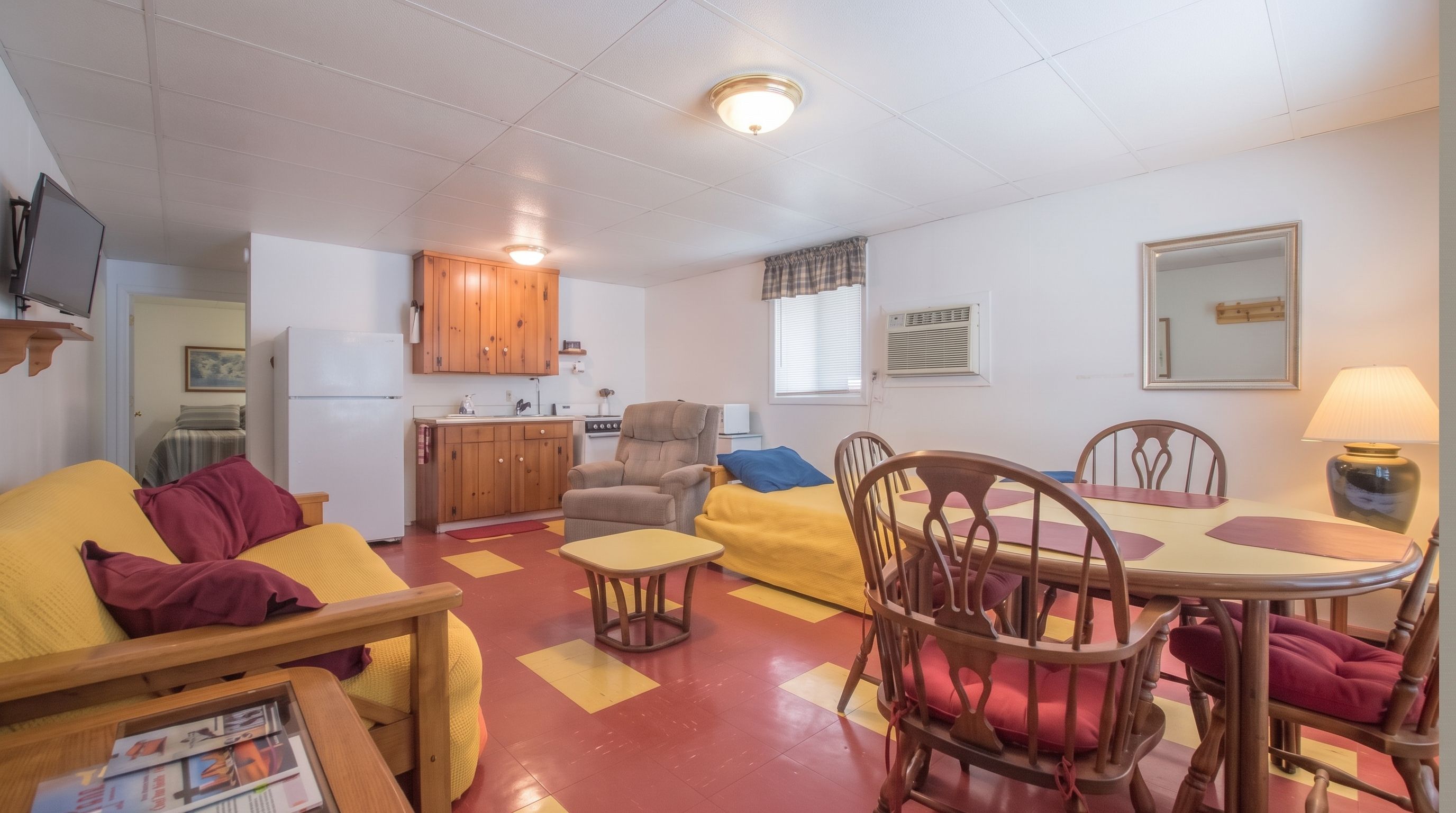 A compact living space with a sofa, armchair, dining table, and kitchenette.