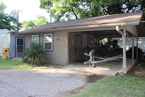 A single-story house with a garage, a small garden, and a boat trailer.