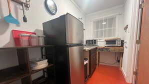 A compact kitchen with a refrigerator, microwave, and a small countertop. - Studio #21-Efficiency (Kingsland)