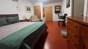 A hotel room with a bed, a chair, a desk, a dresser, and a wardrobe. - Studio #21-Efficiency (Kingsland)