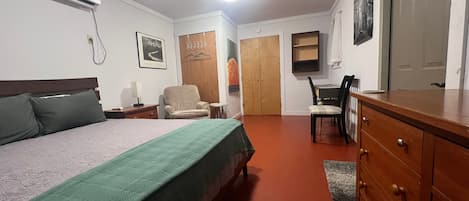 A hotel room with a bed, a chair, a desk, a dresser, and a wardrobe.