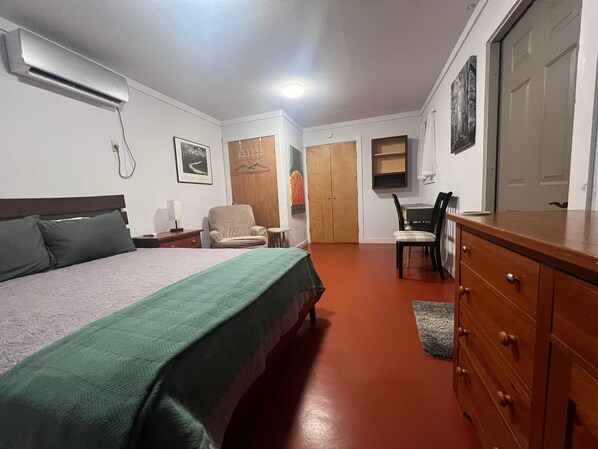 A hotel room with a bed, a chair, a desk, a dresser, and a wardrobe.