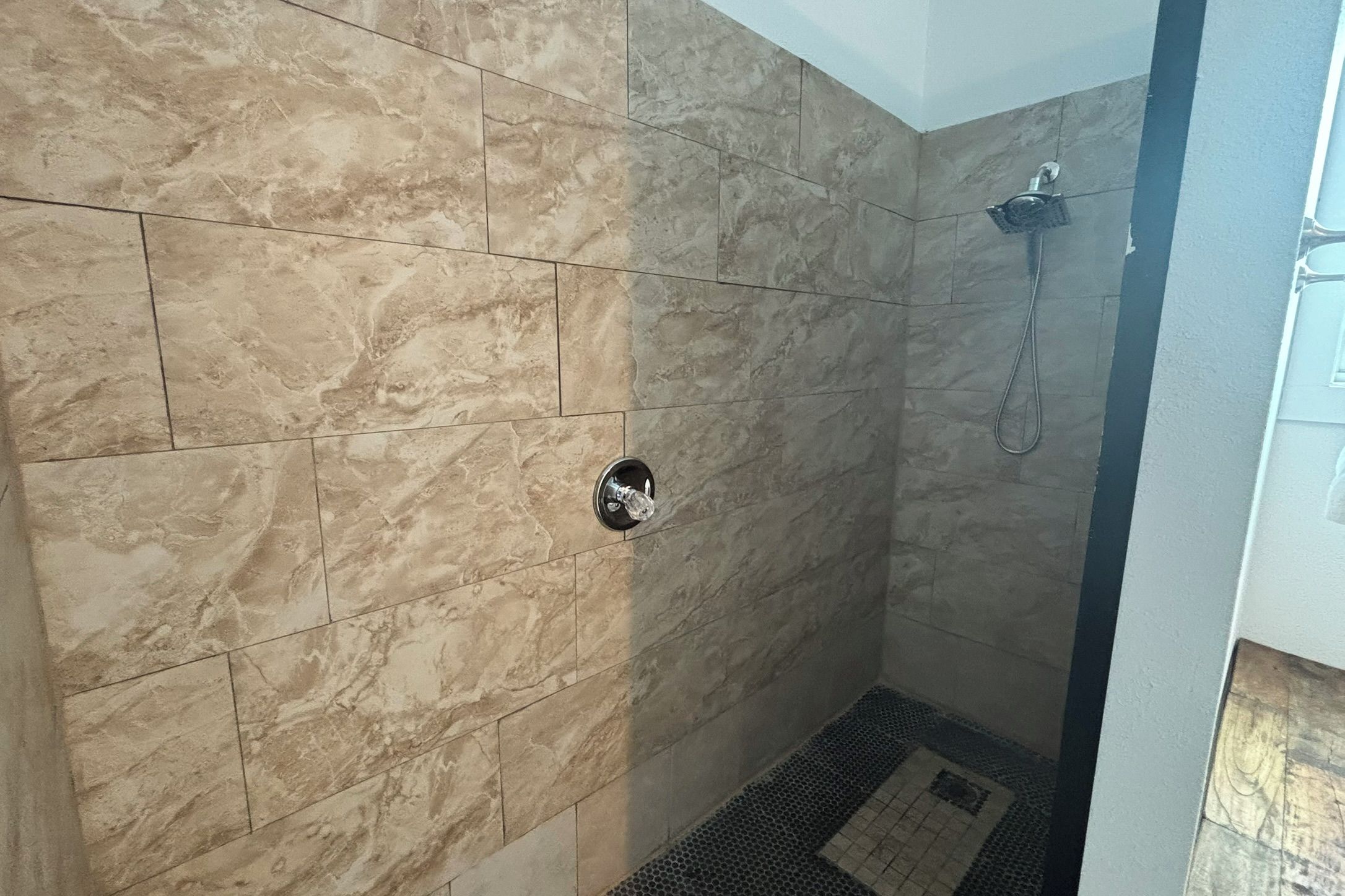 A shower area with a tiled wall and a showerhead.
