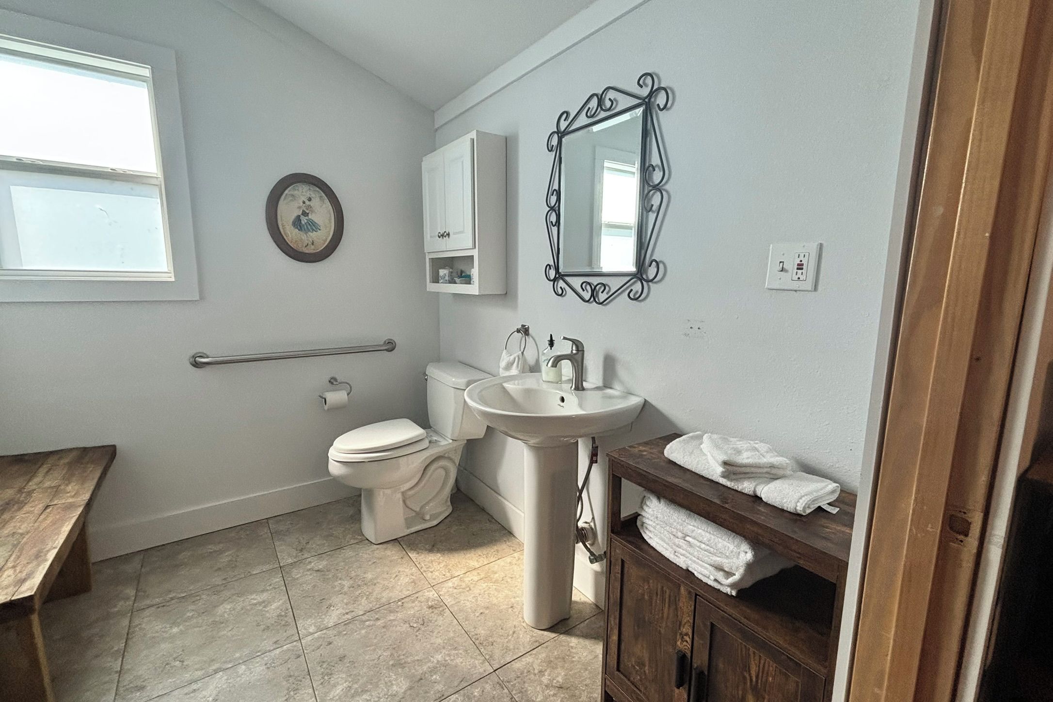 A bathroom with a toilet, sink, vanity, and a window.