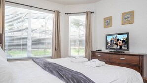 A hotel room with two beds, a television, and large windows with curtains. - Your Dream Family Vacation Home – 5BR, 5BA & Sun-Filled South-Facing Pool! (Kissimmee)