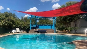 A swimming pool with a blue deck and a red canopy.