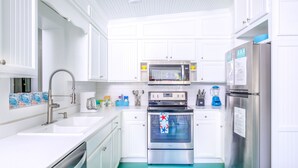 Una cocina moderna con armarios blancos, electrodomésticos de acero inoxidable y encimera azul.