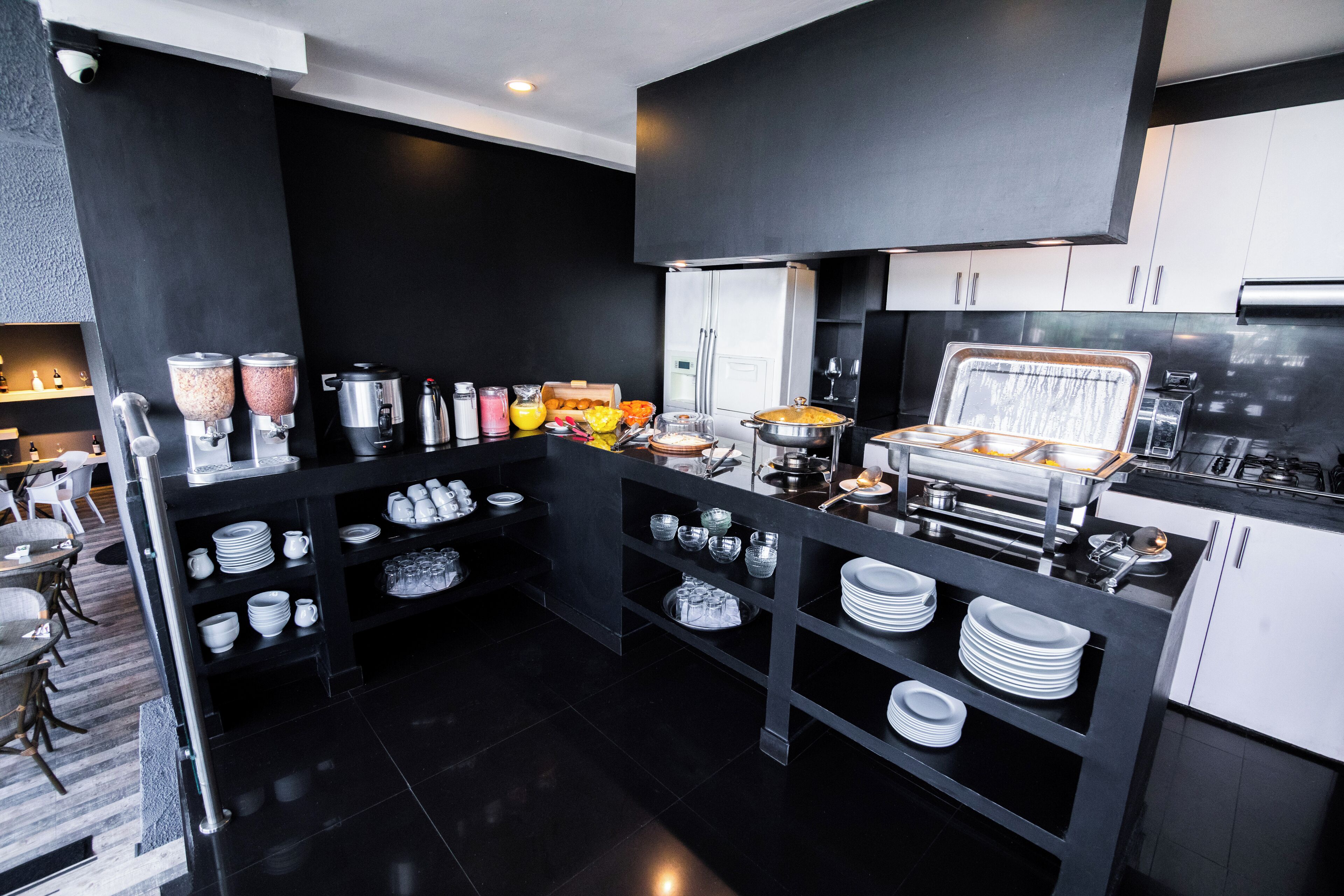 A modern kitchen with black and white cabinetry, a buffet setup, and various kitchen appliances.