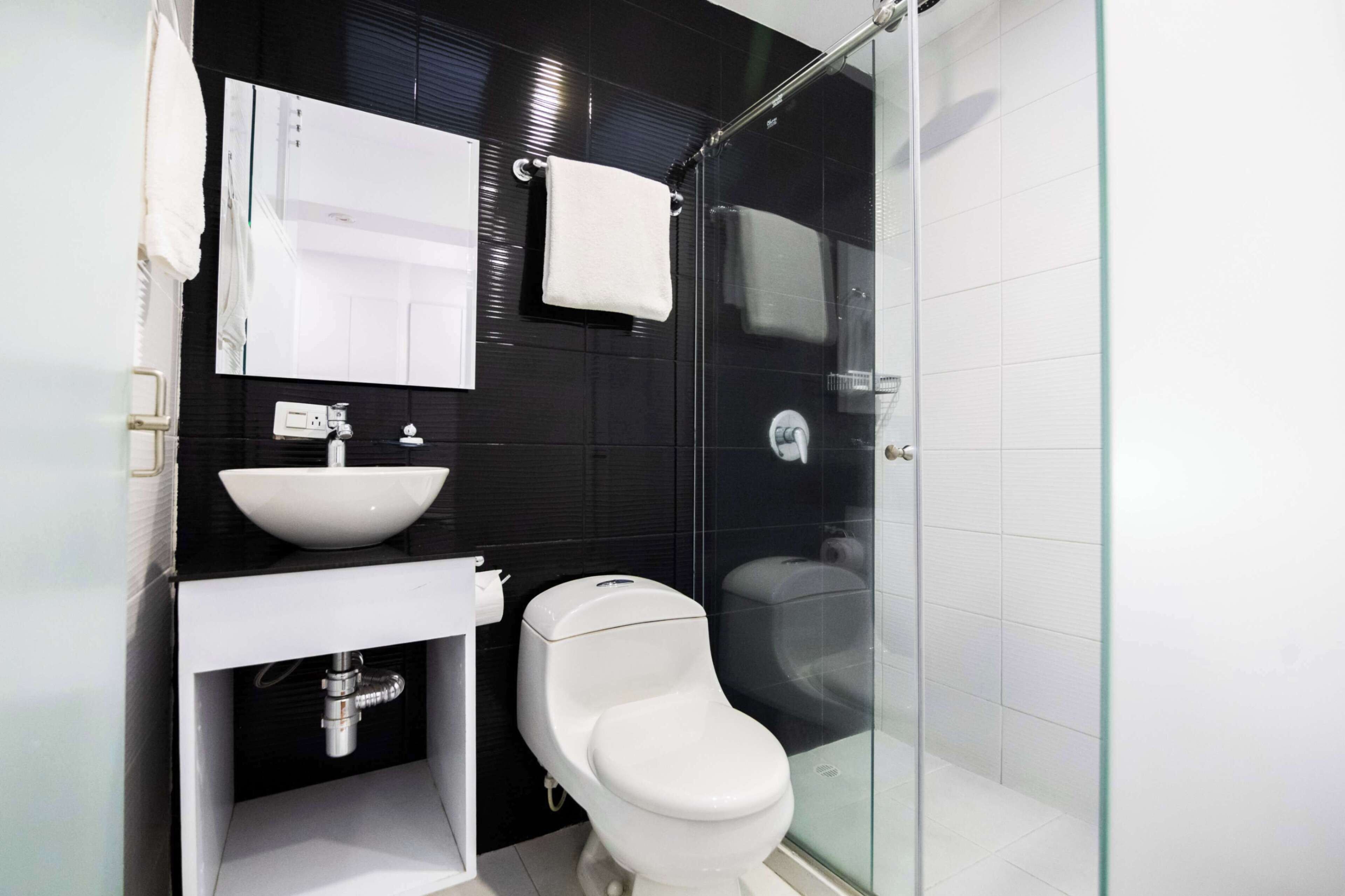 A modern bathroom with a glass-enclosed shower, a white sink, and a toilet.