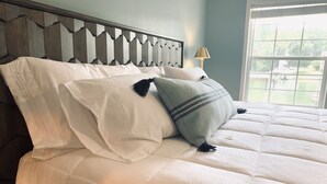 Una cama con ropa de cama blanca y un cabecero decorativo.