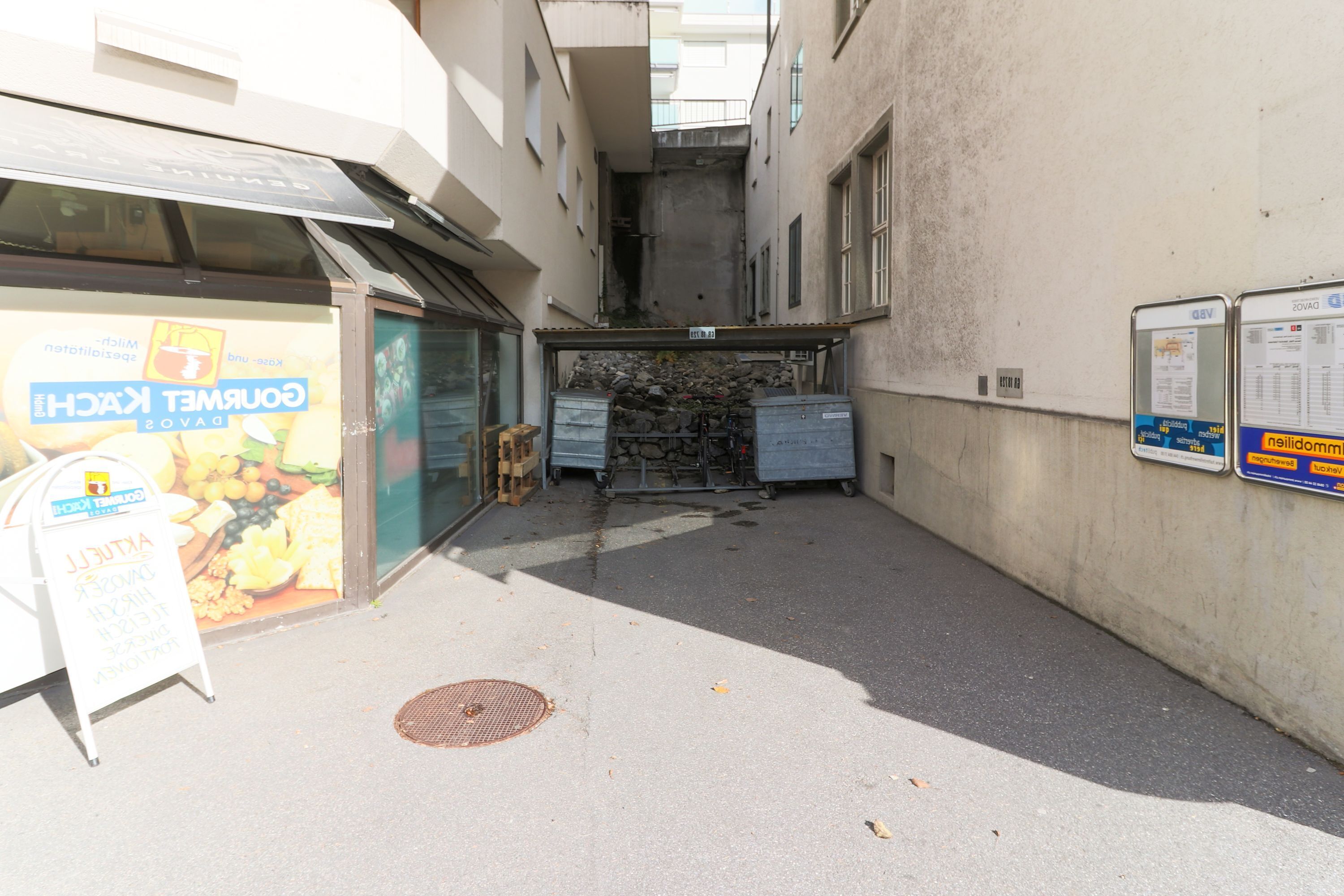 A narrow alleyway with a storefront on the left and a signboard on the right.