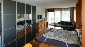 Una habitación de hotel moderna con una cama, un escritorio de madera, un televisor y un sofá.