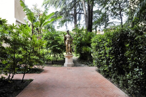 A statue in a garden with a brick pathway.