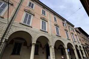 A historic building with a classical facade, featuring multiple arches and a symmetrical window arrangement.