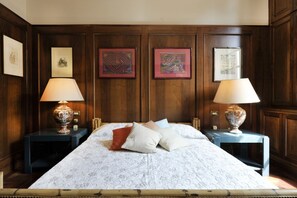A neatly made bed with a patterned bedspread, two bedside tables with lamps, and framed artwork on the walls.