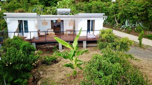 A modern house with a deck, surrounded by lush greenery. - Charming chalet with large terrace and breathtaking sea view (Saint-Leu)