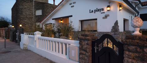 Un edificio con fachada de piedra y exterior blanco, con la leyenda 'La Playa Suites'.