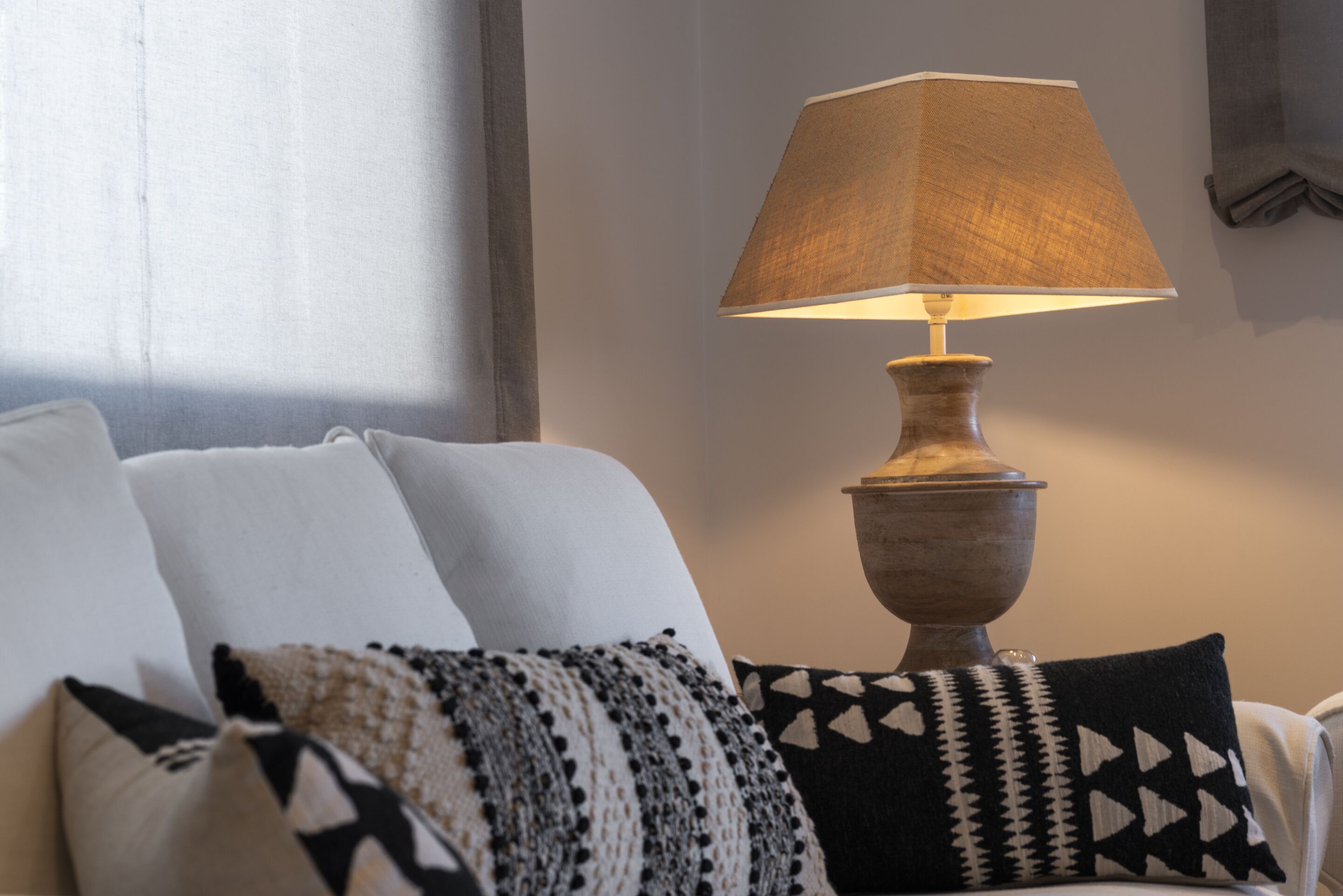 A room with a sofa, a lamp, and patterned cushions.