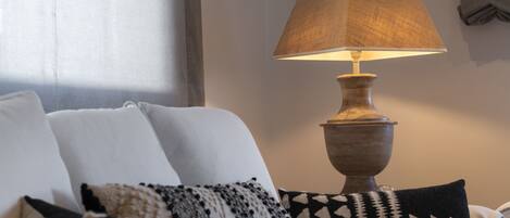 A room with a sofa, a lamp, and patterned cushions.