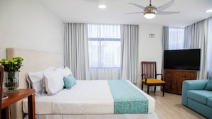 Una habitación de hotel con cama, televisión, sofá y ventilador de techo.
